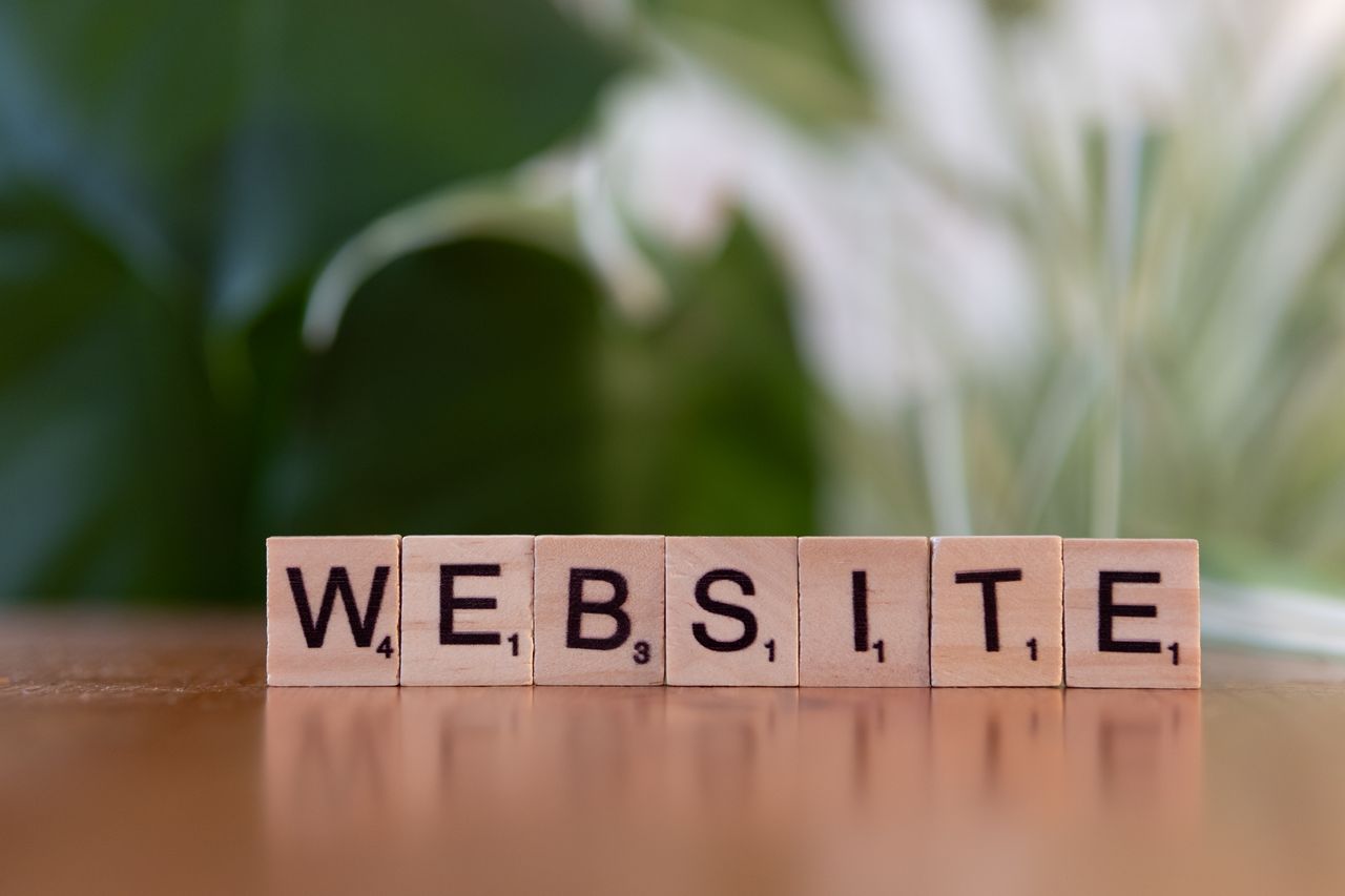 Des lettres de Scrabble posées sur une surface en bois composent le mot Website, illustrant la communication numérique.